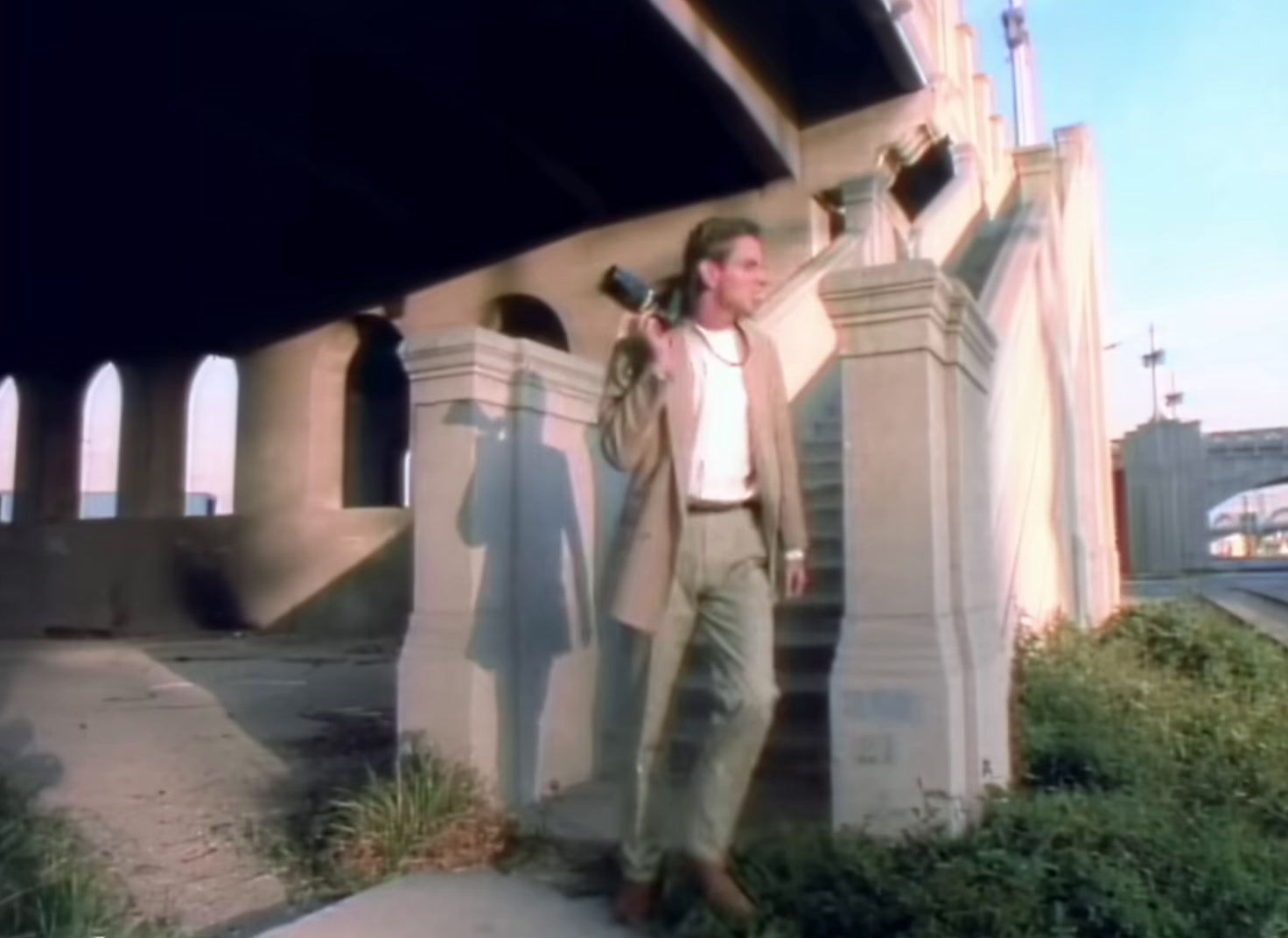 a man standing on the side of a road next to a bridge