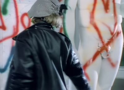 a man standing next to a wall covered in graffiti