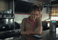 a woman sitting at a counter using a cell phone