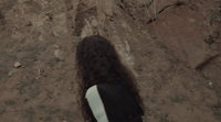 a woman with long hair standing in the dirt