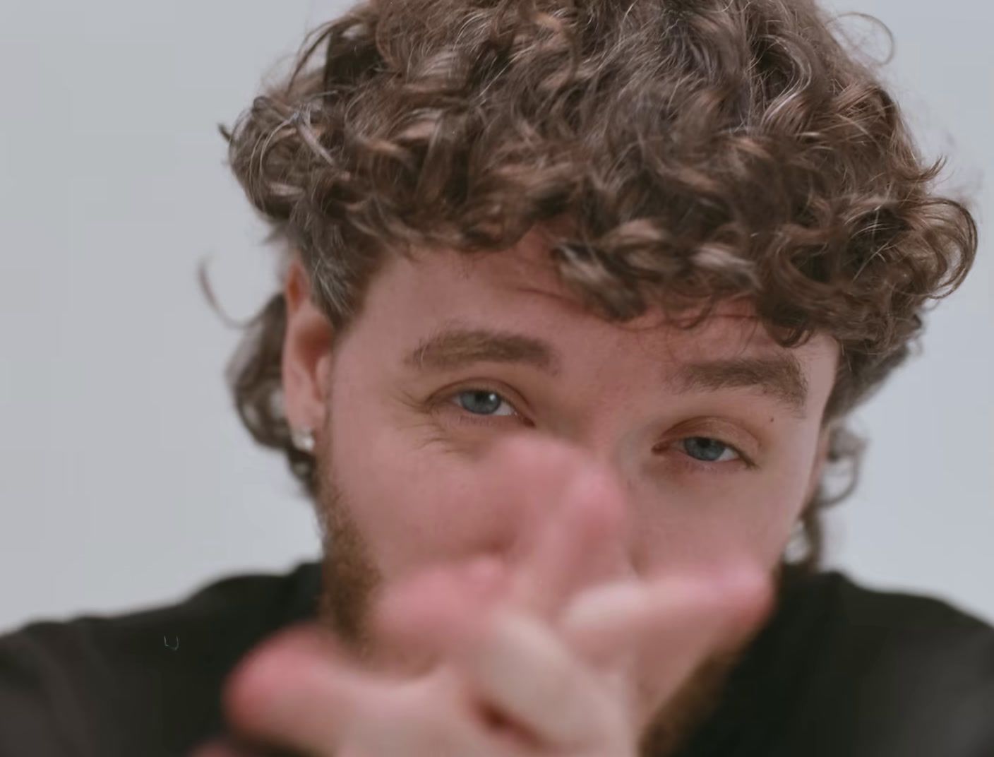 a man with curly hair making a hand gesture