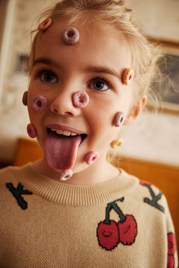 a little girl with her tongue out and her face covered in doughnuts