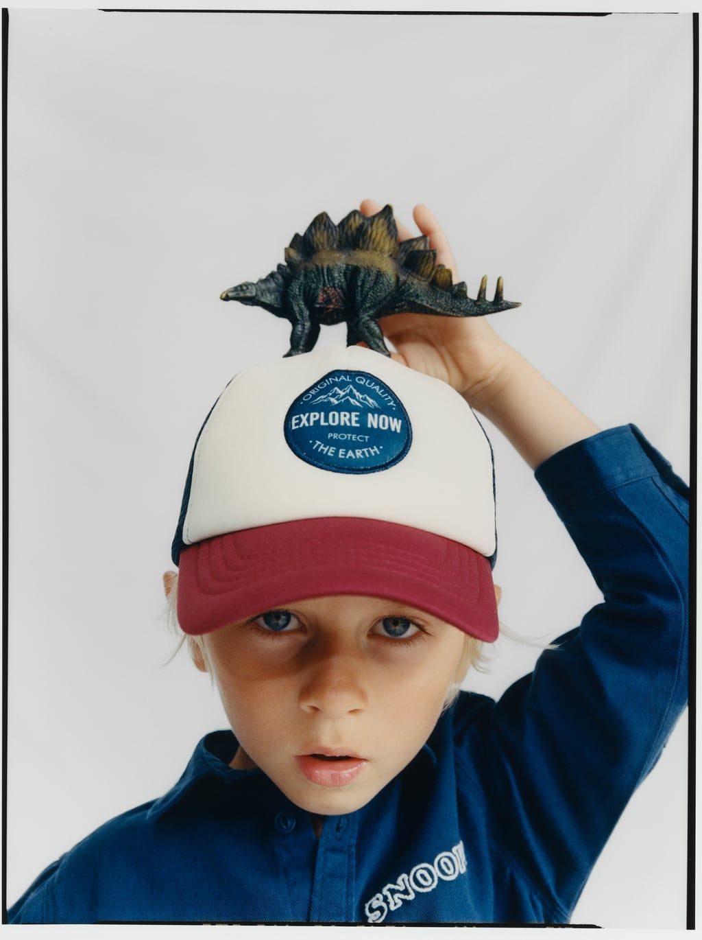 a young boy wearing a hat with a dinosaur on top of it