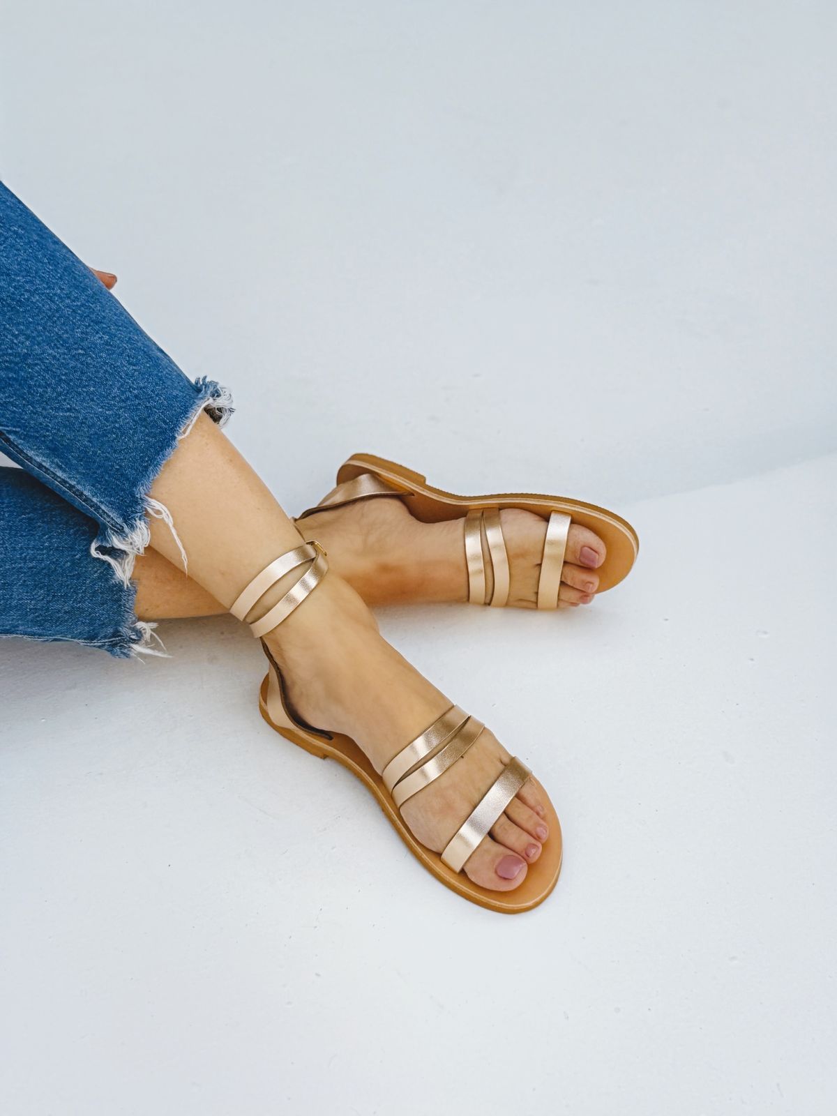 a woman's feet wearing sandals and jeans