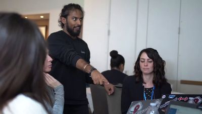 a group of people sitting around a table with laptops