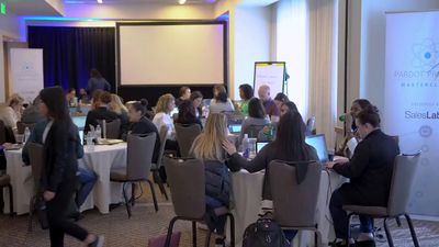 a group of people sitting at tables with laptops