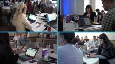 a group of people sitting around a table with laptops