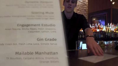 a man standing at a bar with a menu in front of him