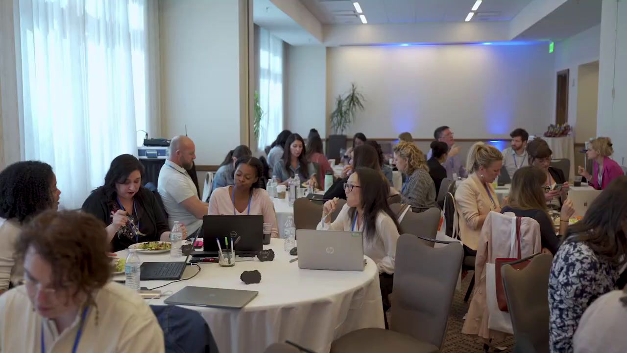 a group of people sitting at tables with laptops