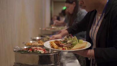 a woman holding a plate of food at a buffet