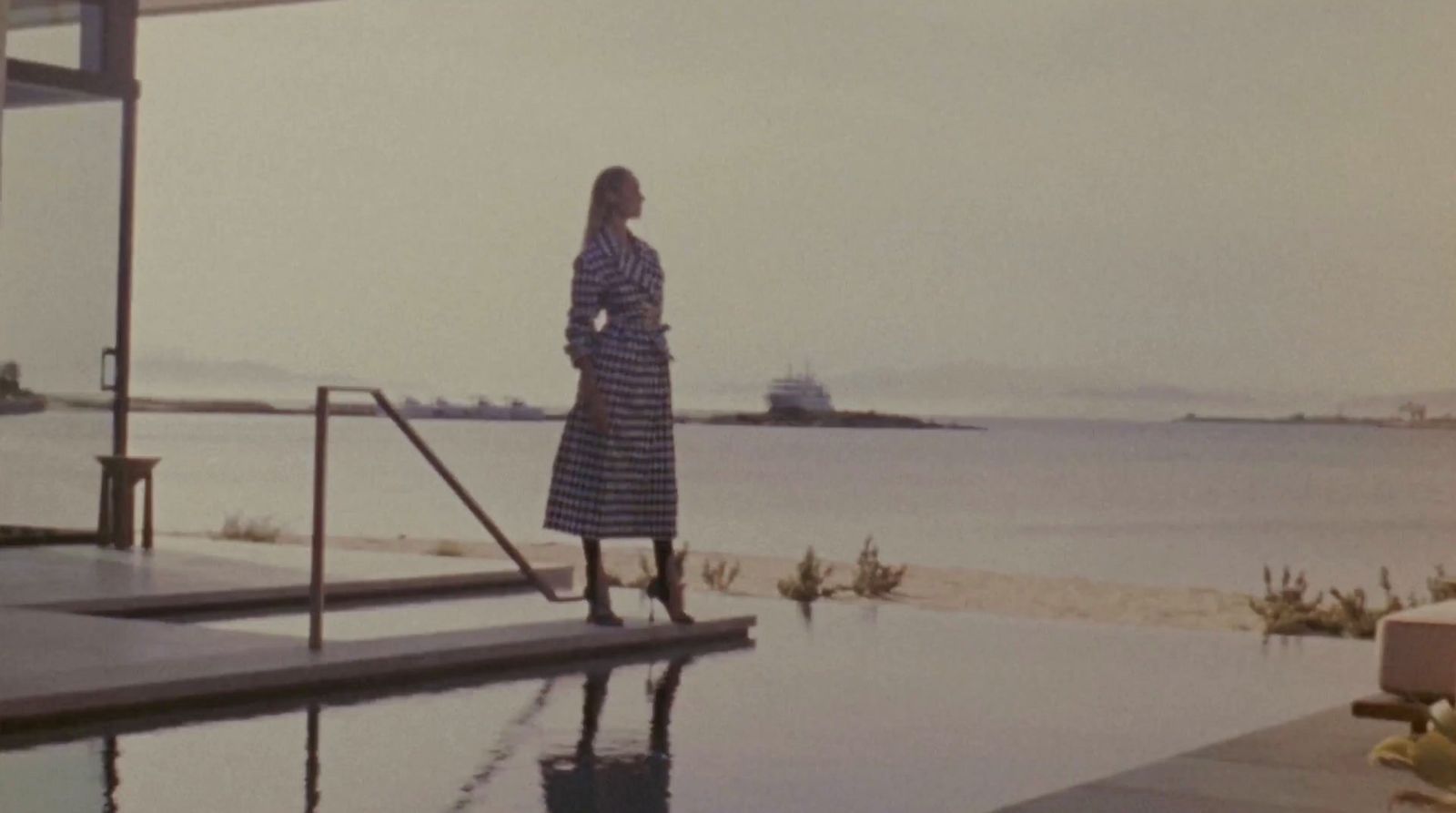 a woman in a striped dress standing by a pool