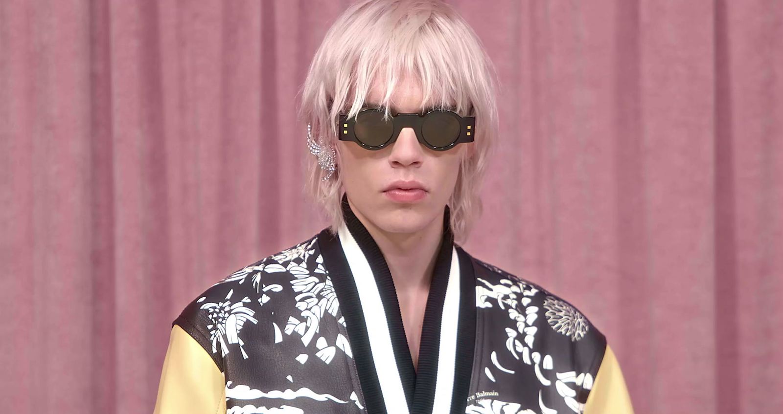 a woman with pink hair wearing sunglasses and a black and yellow jacket