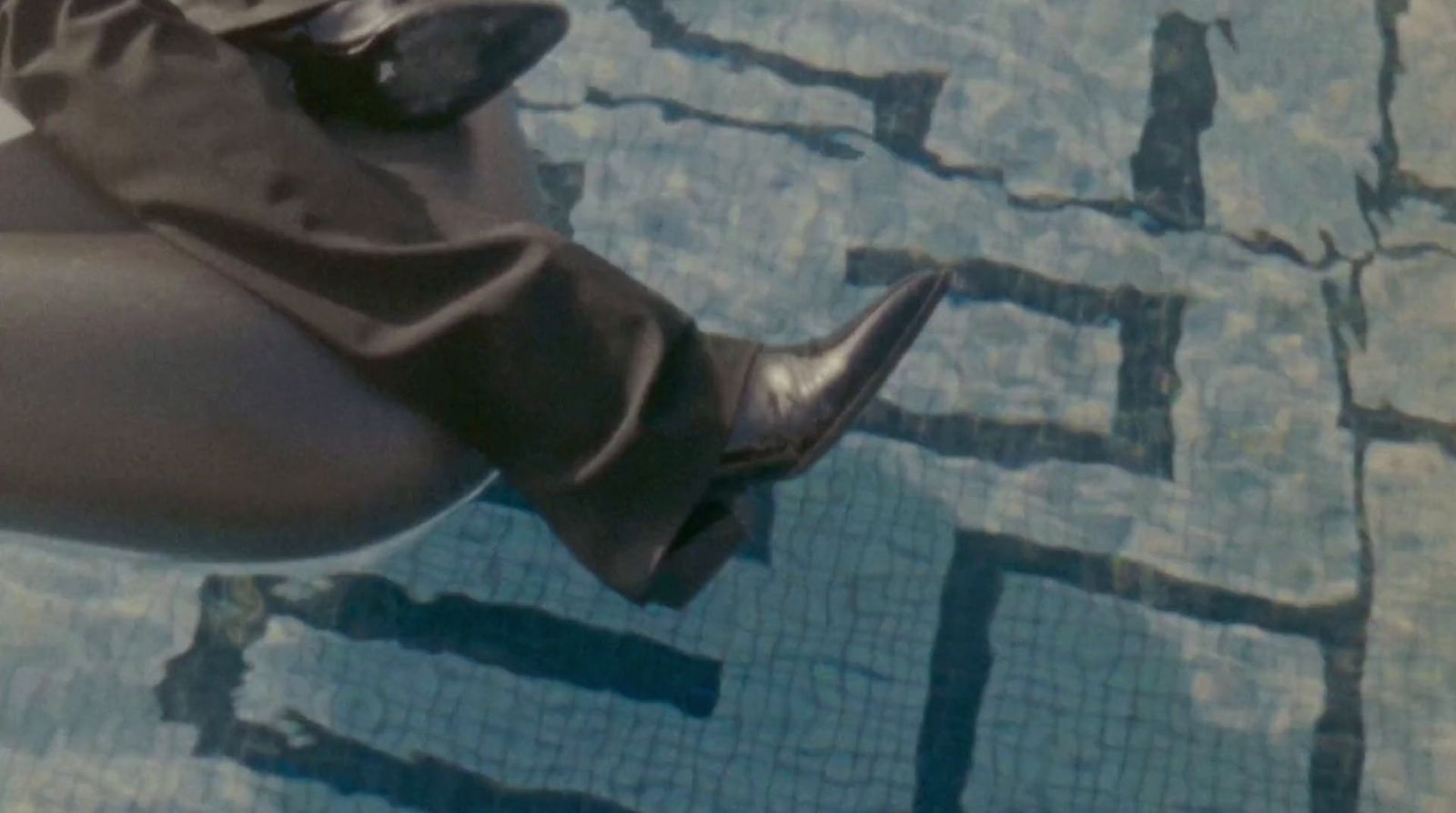 a woman's legs in high heeled boots next to a swimming pool