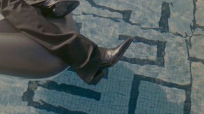 a woman's legs in high heeled boots next to a swimming pool