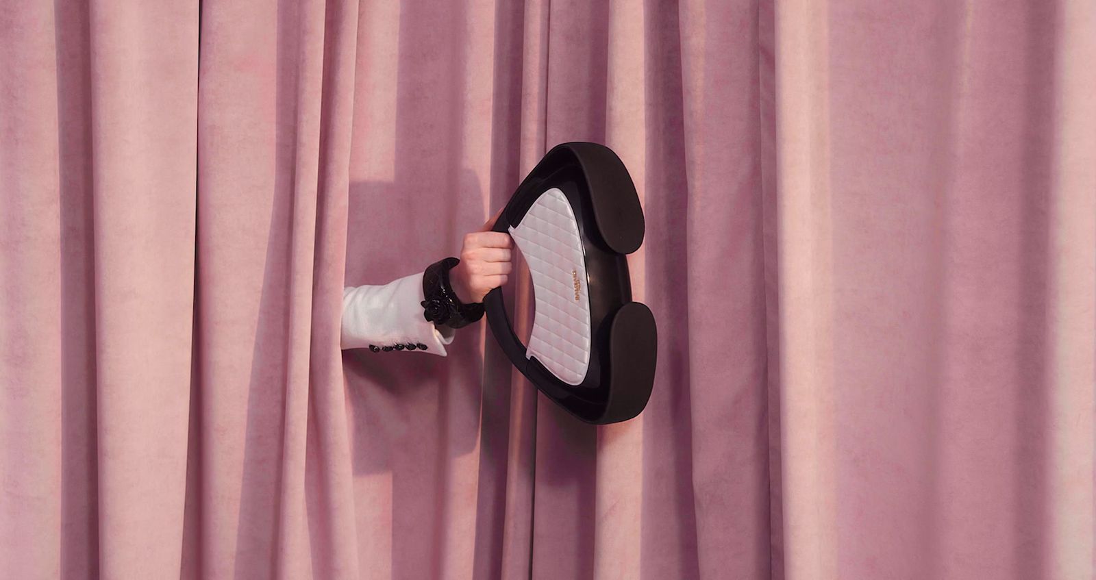 a person holding a hat on top of a curtain