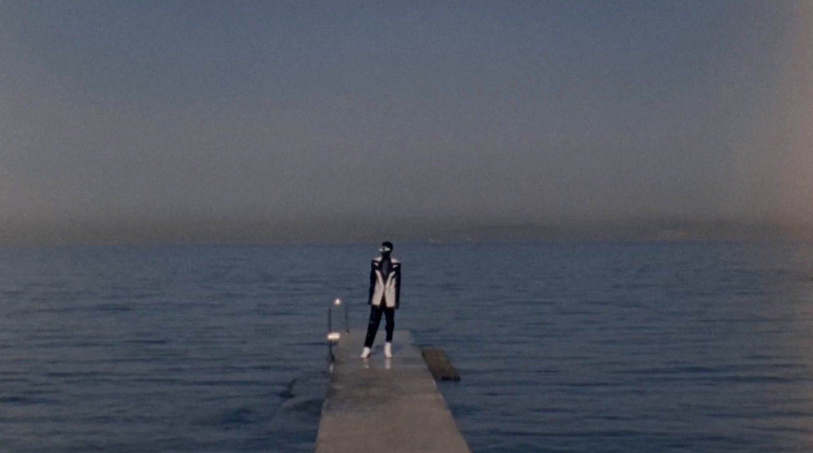 a man standing on a pier in the middle of the ocean