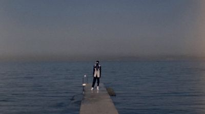 a man standing on a pier in the middle of the ocean