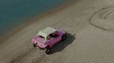 a pink jeep driving down a sandy beach