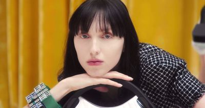 a woman with black hair holding a white bag