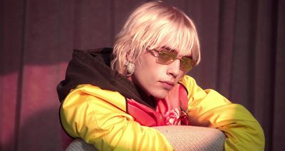 a man with blonde hair and sunglasses sitting on a chair