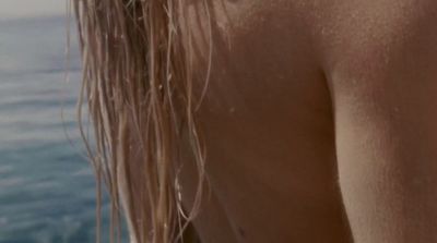 a close up of a woman's back with water in the background