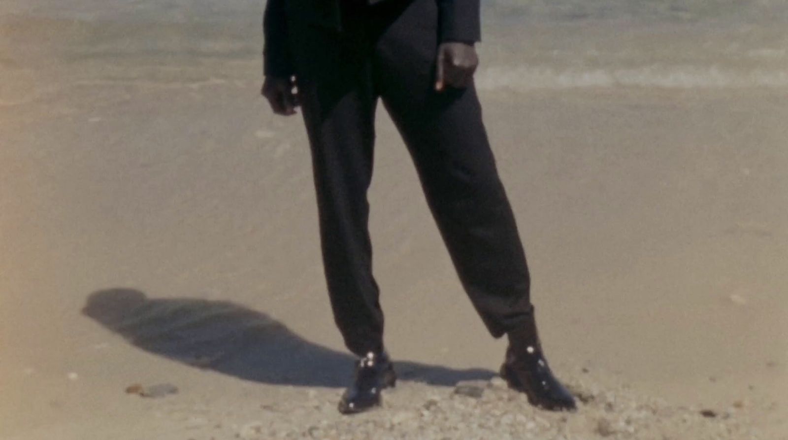 a man in a suit standing on a beach