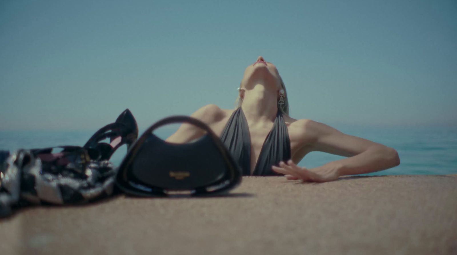 a woman laying on the beach next to a purse