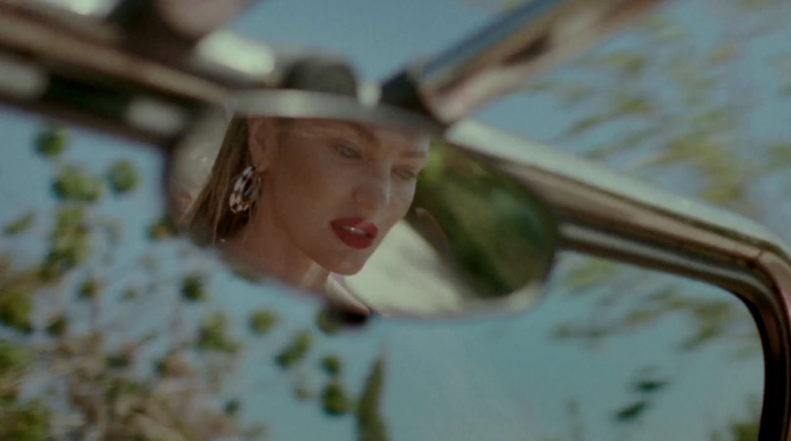 a woman's reflection in the side view mirror of a car