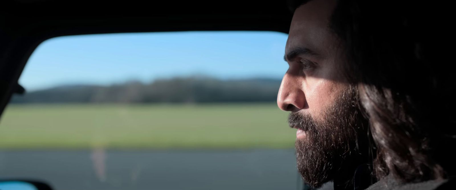 a man with long hair sitting in a car