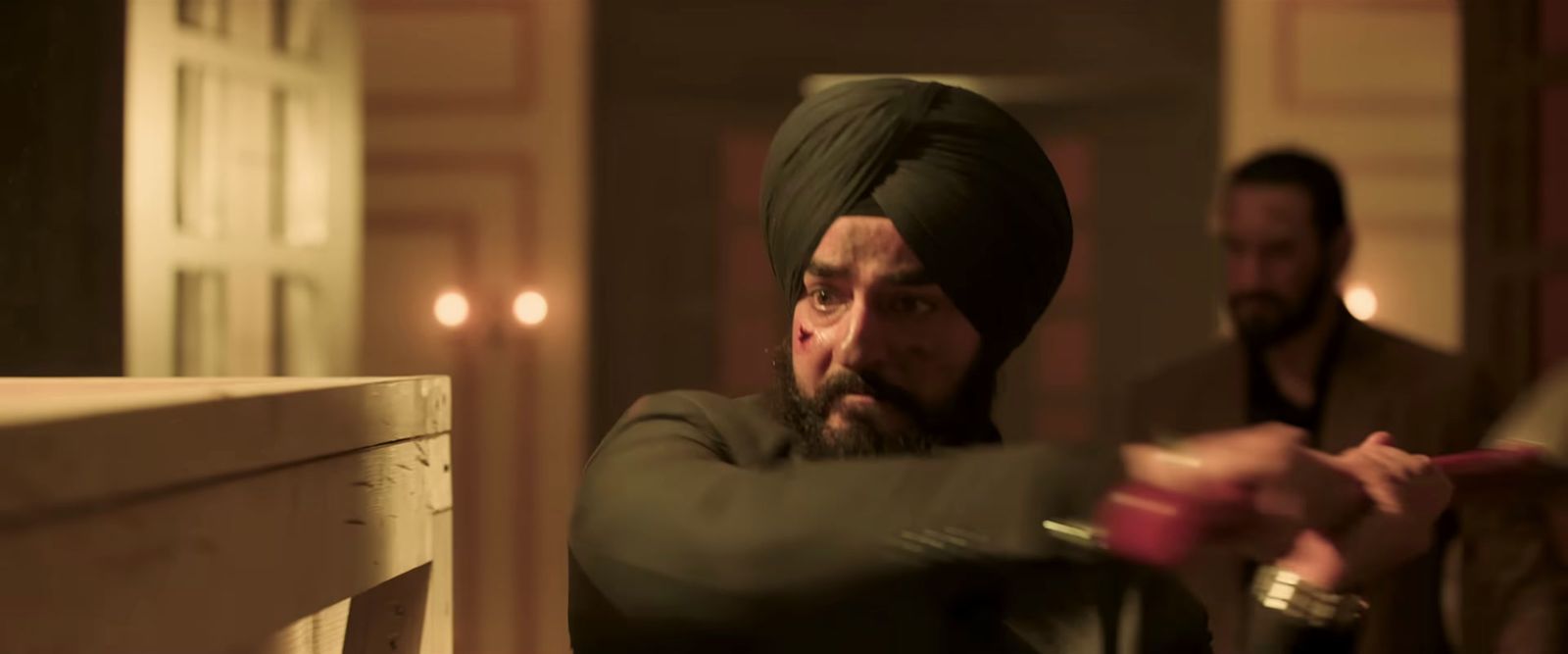 a man in a turban pointing a gun at another man