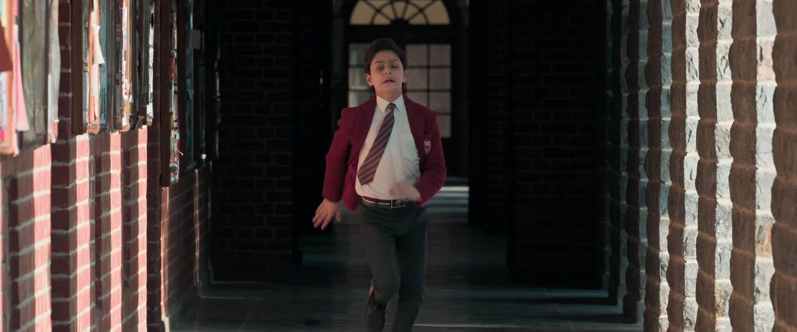 a man in a suit and tie walking through a hallway