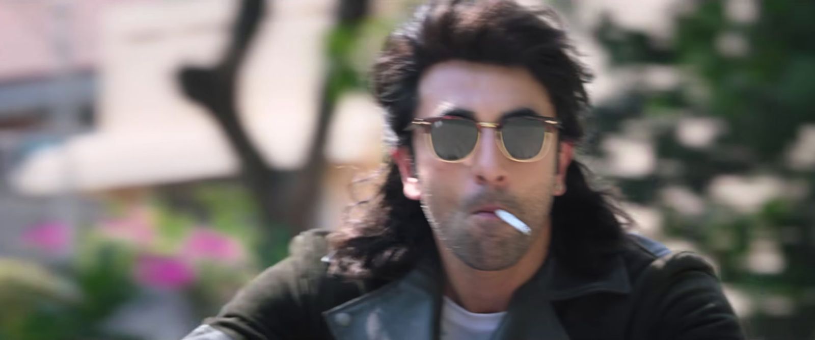 a man with long hair and sunglasses smoking a cigarette