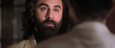 a man with long hair and a beard looking at another man