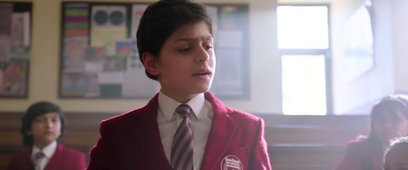 a young boy wearing a red vest and tie