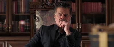 a man sitting in a chair in front of a bookshelf