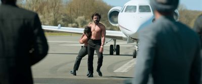 a shirtless man walking towards a small plane