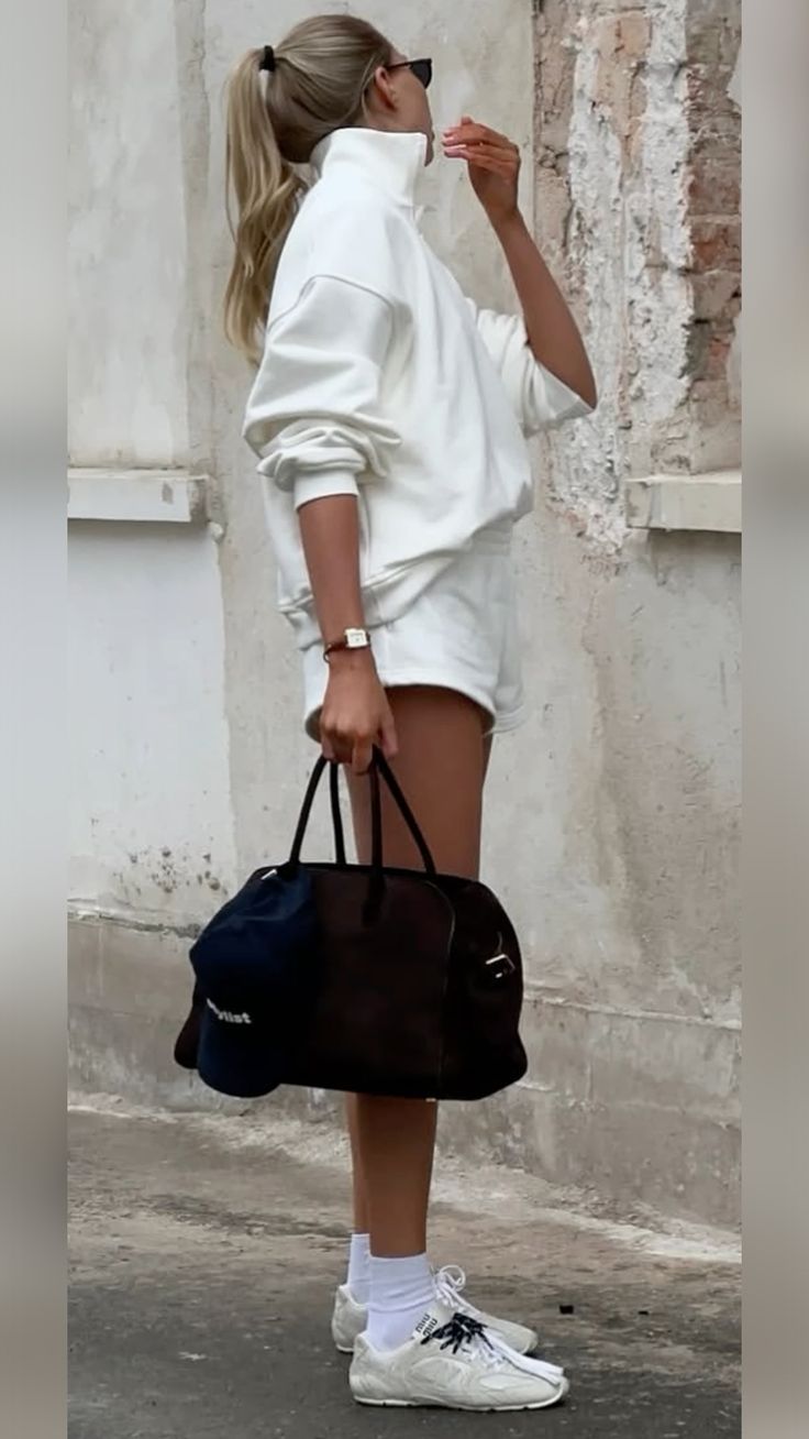 a woman in white is holding a black bag