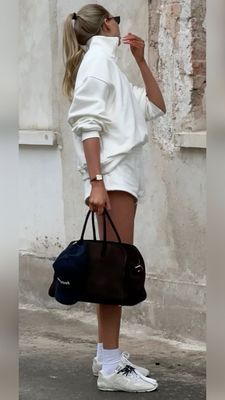 a woman in white is holding a black bag