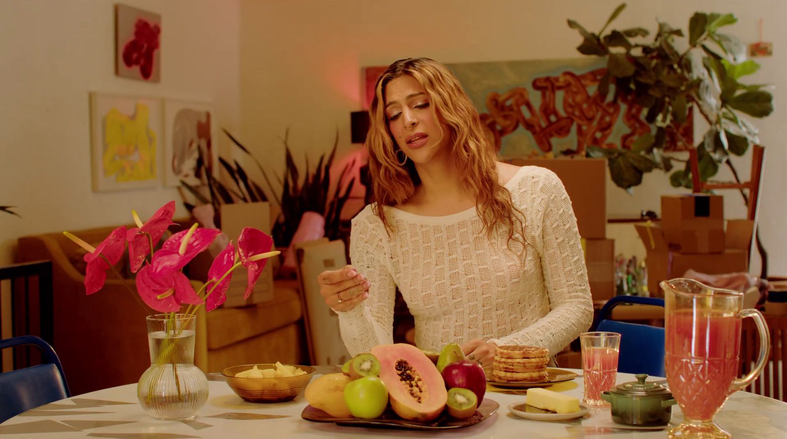 a woman sitting at a table with a plate of fruit