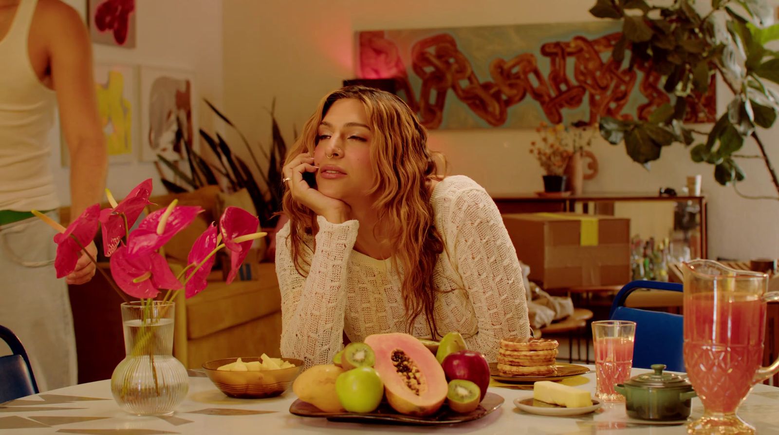 a woman sitting at a table with a plate of fruit