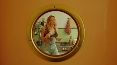 a woman standing in a kitchen in front of a mirror