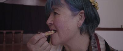 a woman with blue hair eating a piece of food