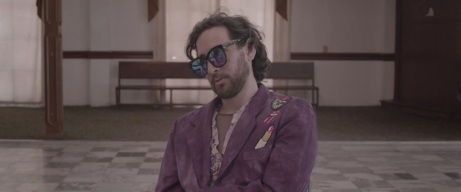 a man in a suit and sunglasses standing in a room