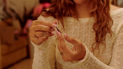 a woman is holding a small piece of jewelry