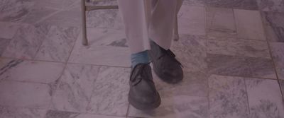 a person standing on a tile floor wearing gray shoes