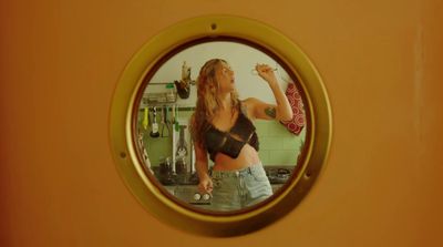 a woman standing in a kitchen looking at herself in a mirror