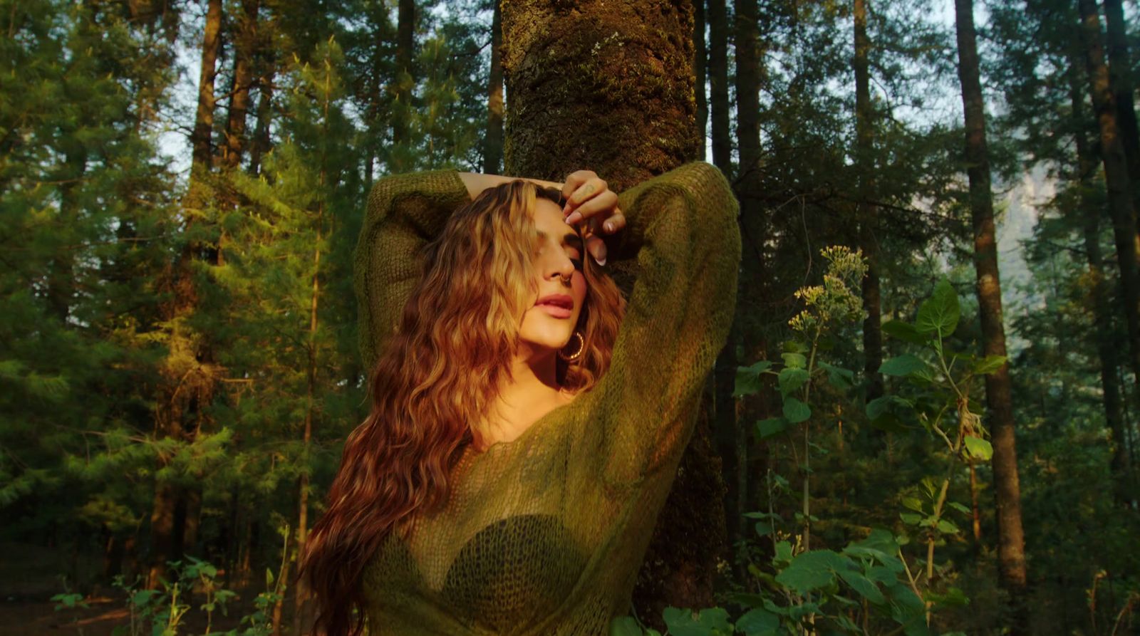 a woman in a green dress standing next to a tree