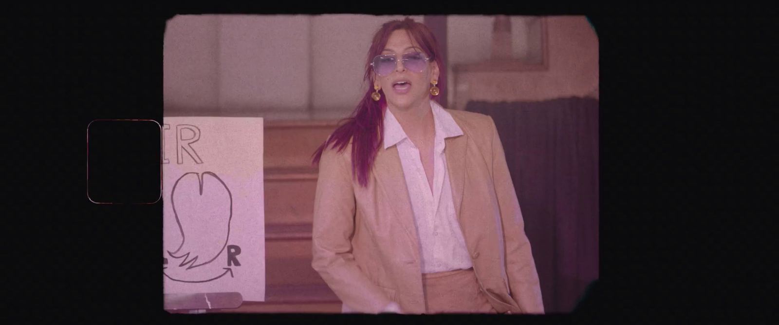 a woman with red hair and glasses standing in front of a sign