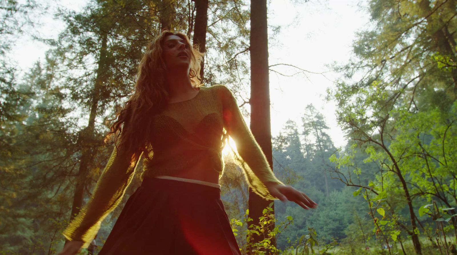 a woman in a black dress standing in the woods