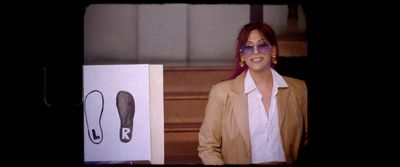 a woman standing next to a box with a pair of shoes on it